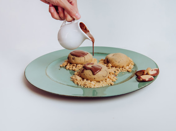 Cookie de Castanha do Brasil, com massa saborizada com cumaru, que é considerada a baunilha do Brasil, muito utilizada por grandes chef no mundo todo, e gotas de chocolate meio amargo, recheado com brigadeiro de castanha.
